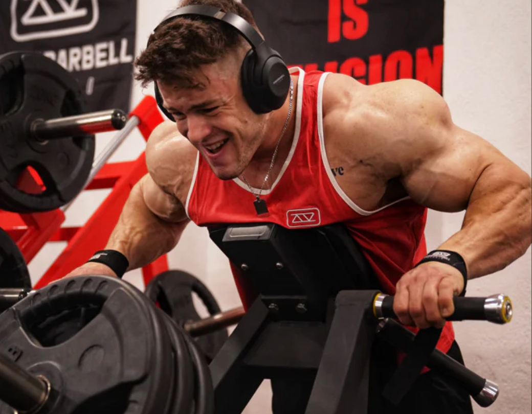 Cascos over-ear en un gimnasio mientras un atleta hace flexiones con mancuernas